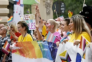 A vibrant assembly of people displaying rainbow flags, symbolizing solidarity and the leadership of women in community projects.